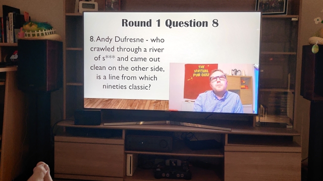 Screen of the Virtual Pub Quiz question with video of the host. Text on screen, Round 1 Question 8. Andy Dufresne - who crawled through a river of s*** and cam out clean on the other side, is a line from which nineties classic?